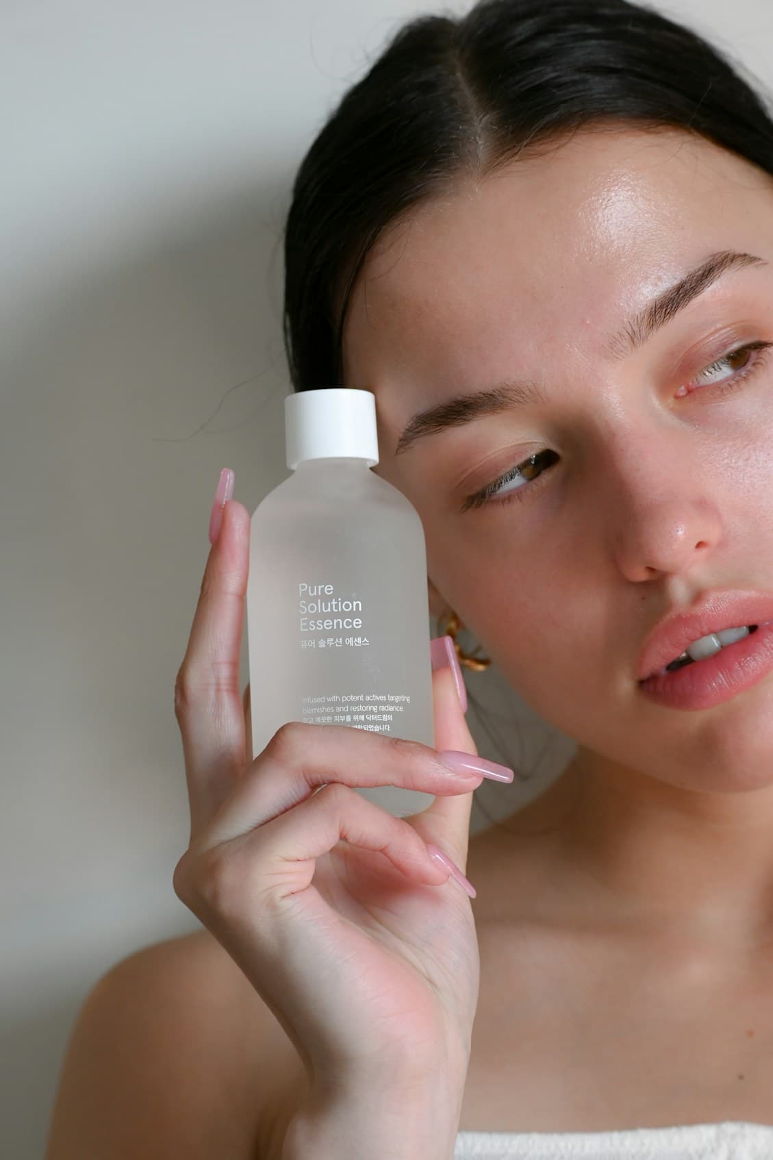 Model holding a frosted skincare bottle