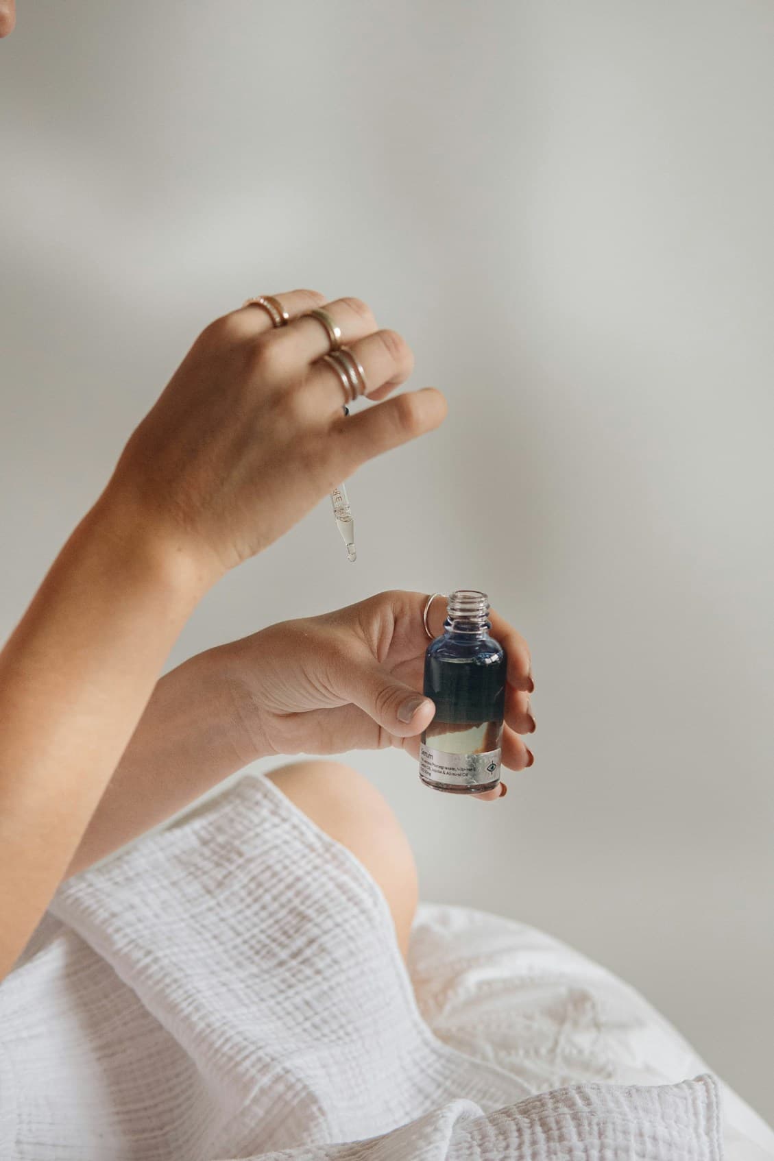 Hands holding a dropper bottle of serum